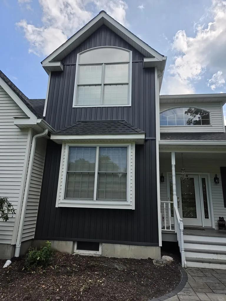 Finished vertical board and batten siding in dark navy on a two-story home addition