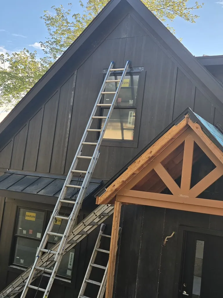 Dark craftsman-style gable with a cedar truss entry portico under a metal roof