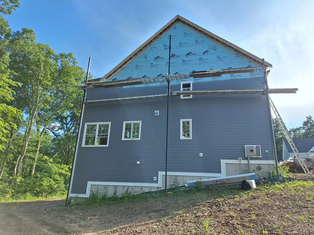 New construction gable with blue-gray board and batten siding and house wrap