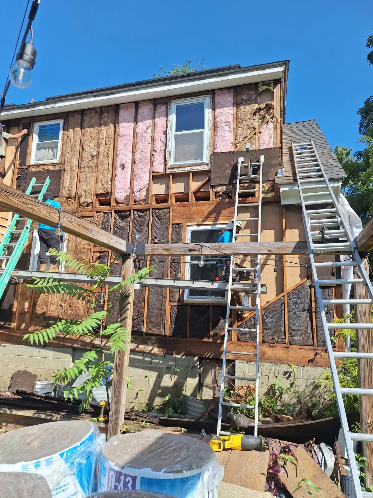 Crew performing an exterior remodel with insulation and sheathing exposed