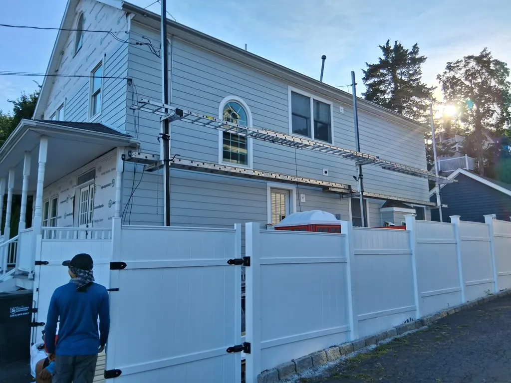 Blue-gray siding installation nearing completion in golden hour light